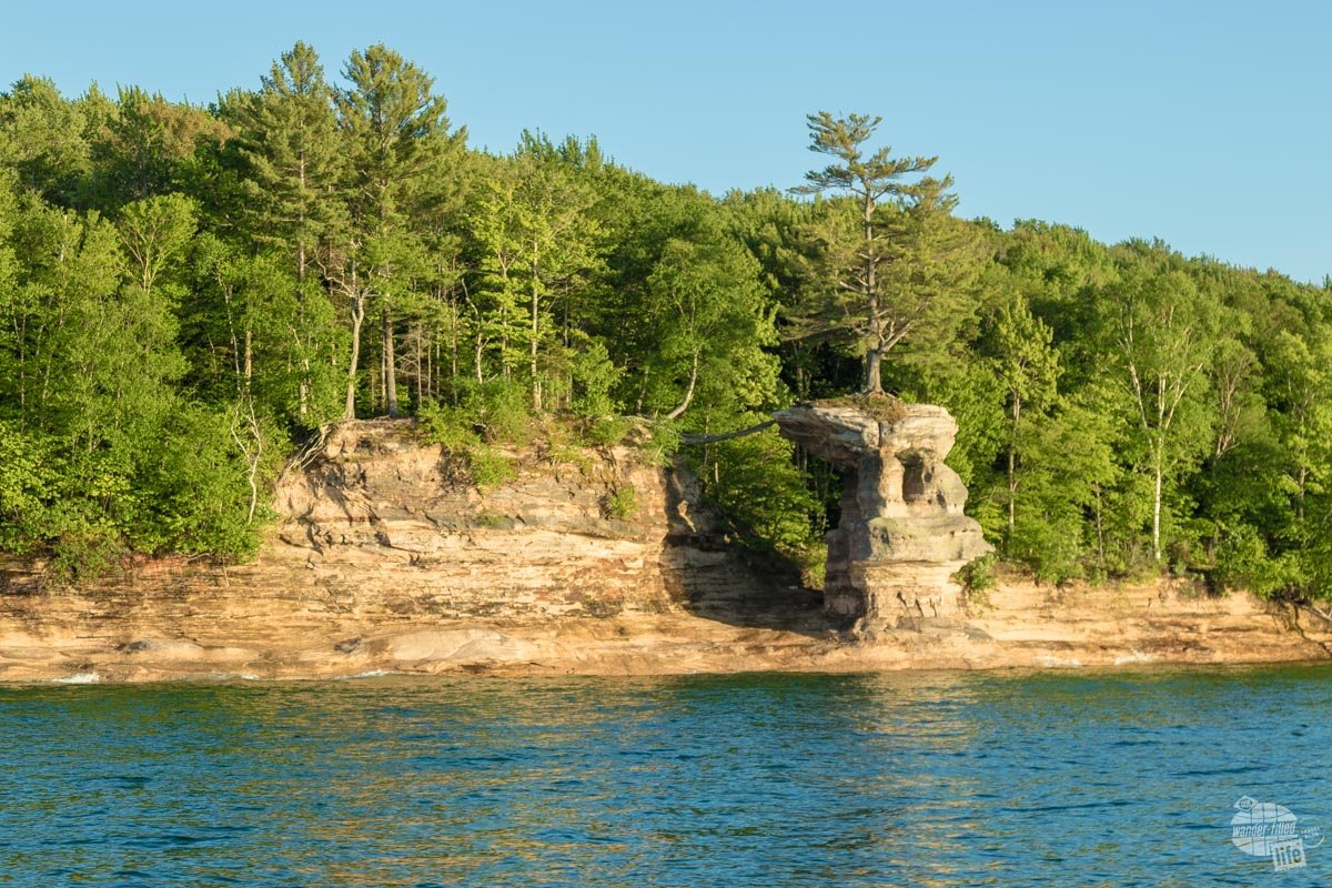 Chapel Rock sits atop a rock with one root spreading to land keeping it alive.