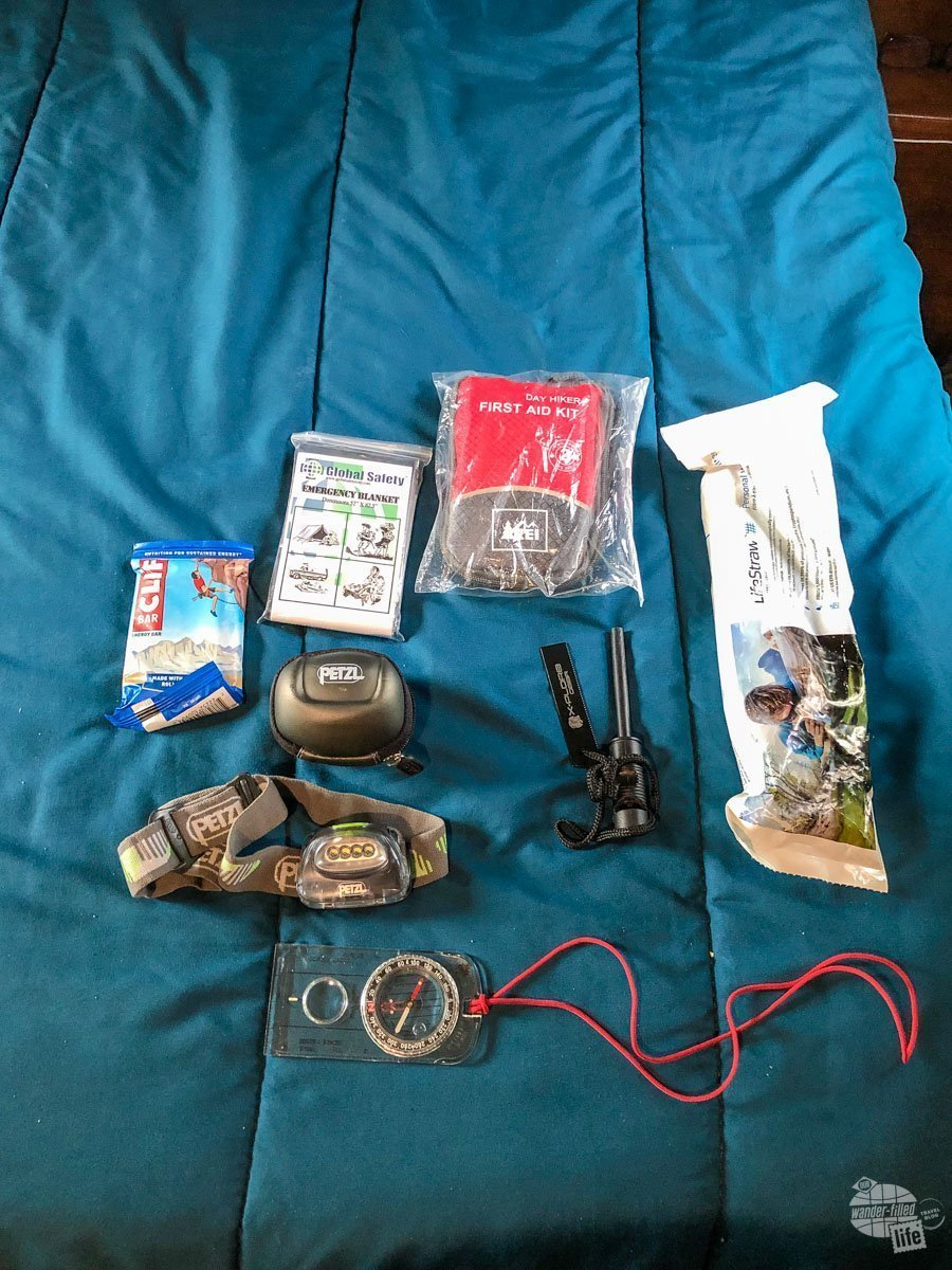 This is gear I always have in my pack: a space blanket, a first aid kit, a LifeStraw, a fire starter, a compass and a headlamp plus some extra food.