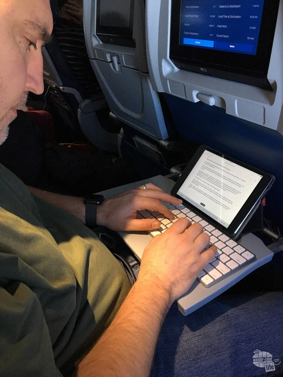 Grant working on a blog post on a flight. Using an iPad Mini and a Magic Keyboard in lieu of a laptop. It took us a while before we could save for a good laptop.